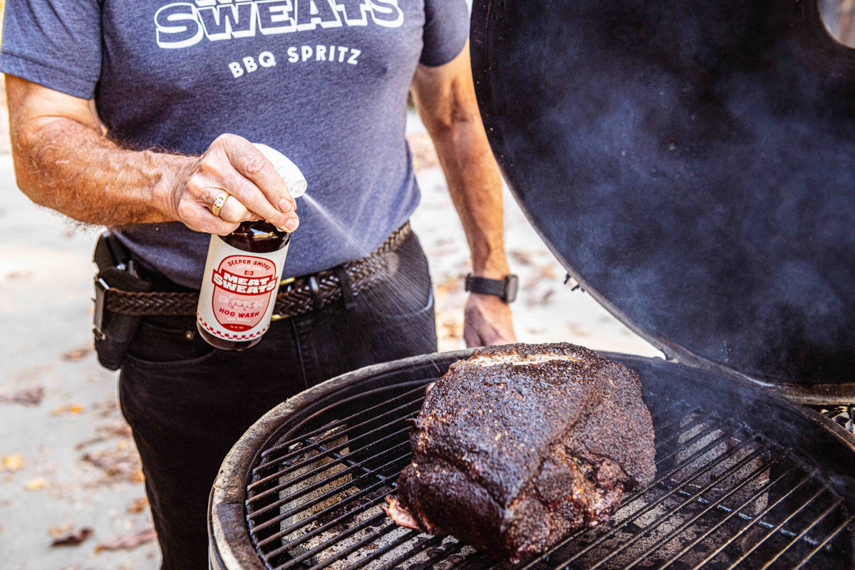 Meat Sweats Hog Wash BBQ spritz being sprayed onto pork on a smoker